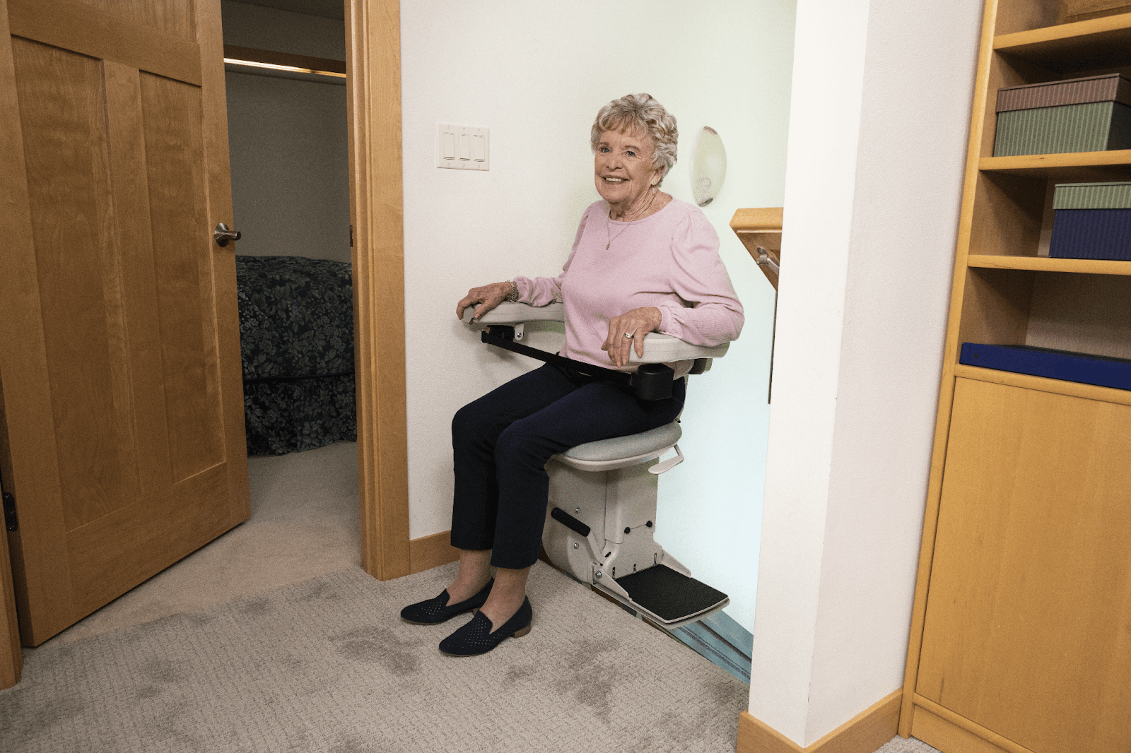 A woman smiling after she just rode up her stair lift